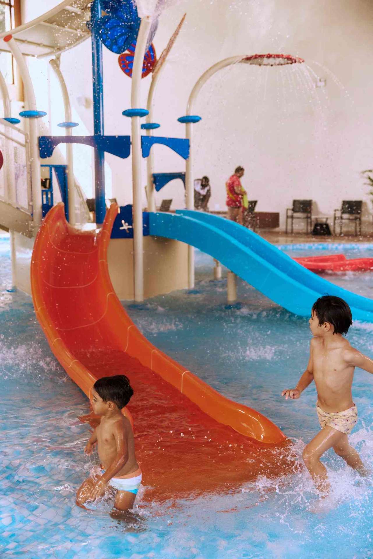 Crianças nos escorregadores laranja e azul do Parque Aquático Alpenmare