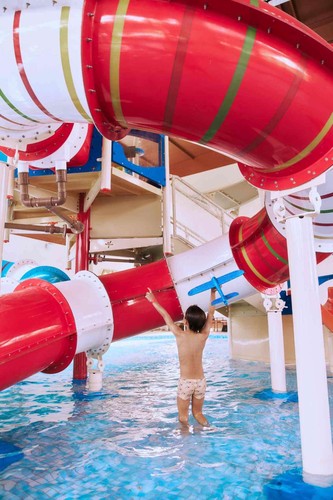 Criança na piscina sob os toboáguas do Parque Aquático Alpenmare