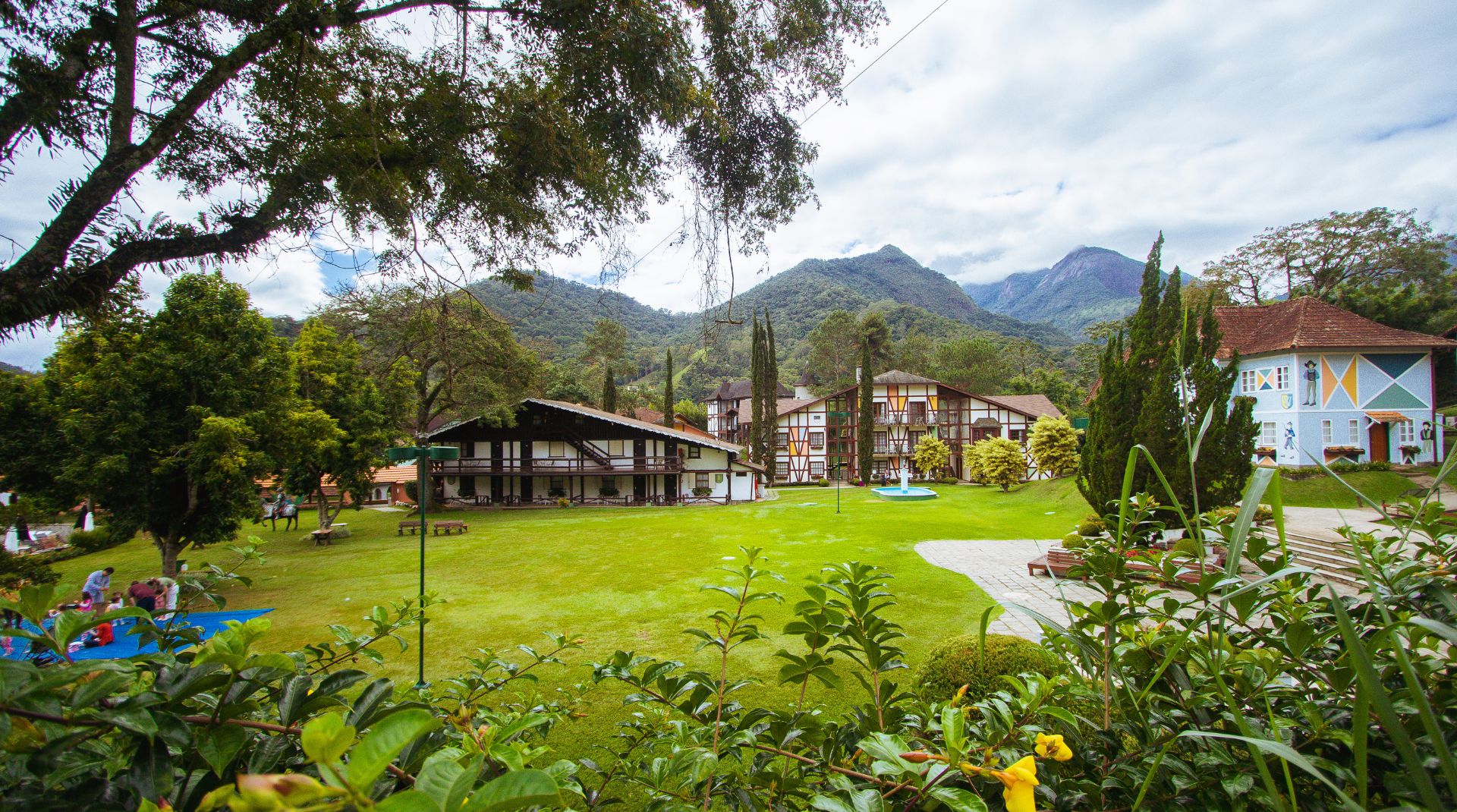 Jardins, gramado e montanhas ao fundo.